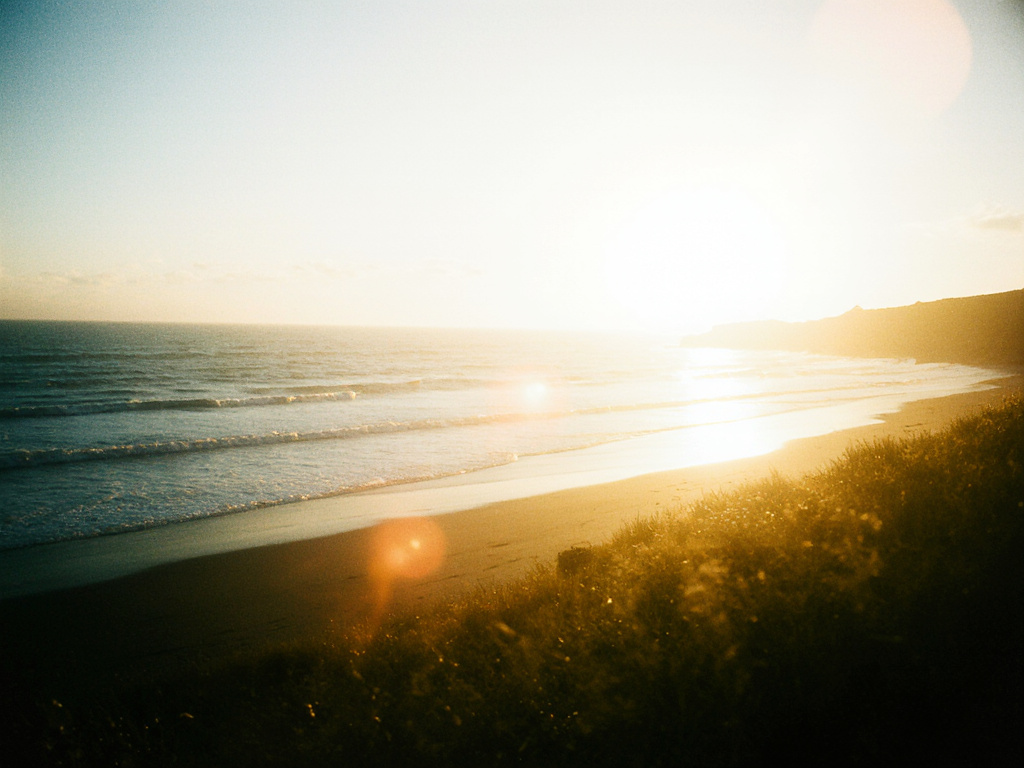 golden_cornish_beach_at_sunset_waves_rolling_in_warm_glow_relaxed_coastal_atmosphere_inviting_and_ho_3bb1ff6b-f616-44da-8297-267efc7b68e3